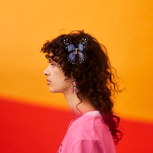 A model with tumbling curls wears a butterfly hairclip for a goddess-like effect