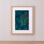 A framed print featuring blue lilies and green foliage on a dark background.