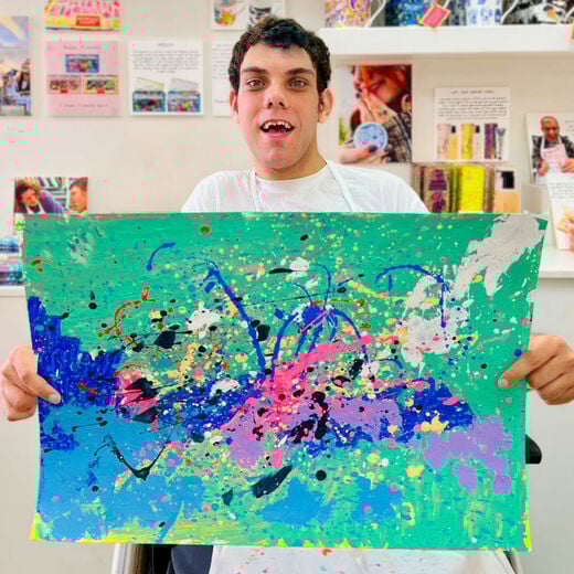 ARTHOUSE Unlimited artist David Bell holding up his abstract artwork to the camera.