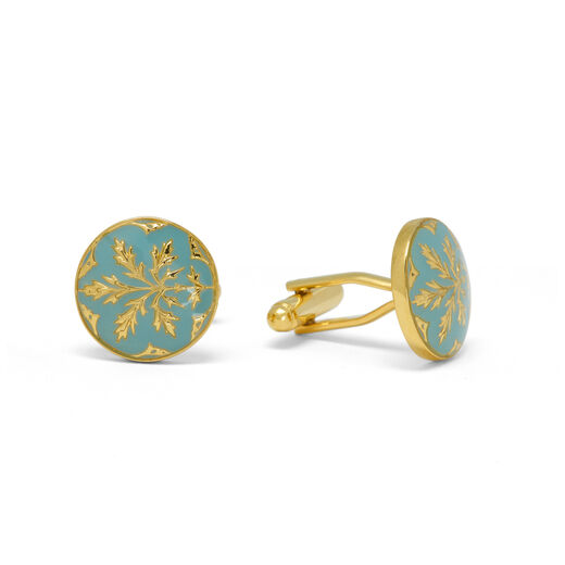 A pair gold cufflinks featuring a botanical motif on a hand painted blue enamel background, encased in a round setting.