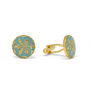 A pair gold cufflinks featuring a botanical motif on a hand painted blue enamel background, encased in a round setting.