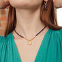A woman wears a short pendant necklace with purple beads.