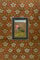Ornate borders of scrollwork and florals surround an intricately painted green and pink bird, in a style typical of Great Mughal india 