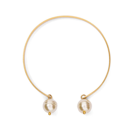 An adjustable bracelet made of a gold band and two white faux pearls descending from its extremities.