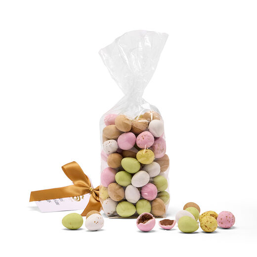 An open pouch of mini chocolate Easter eggs in an assortment of pastel colours. Some of the content is scattered around the tabletop.