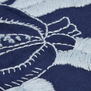 A close up of an embroidery detail on a blue tabe runner.