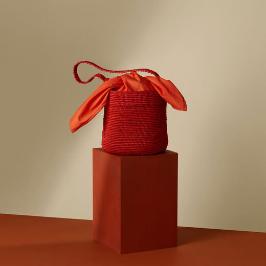 Summer bucket bag, styled on a terracotta coloured plinth.