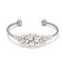A silver cuff bracelet with a cluster of silver beads at its centre.