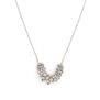 A close up of a silver necklace pendant descending from a delicate chain.