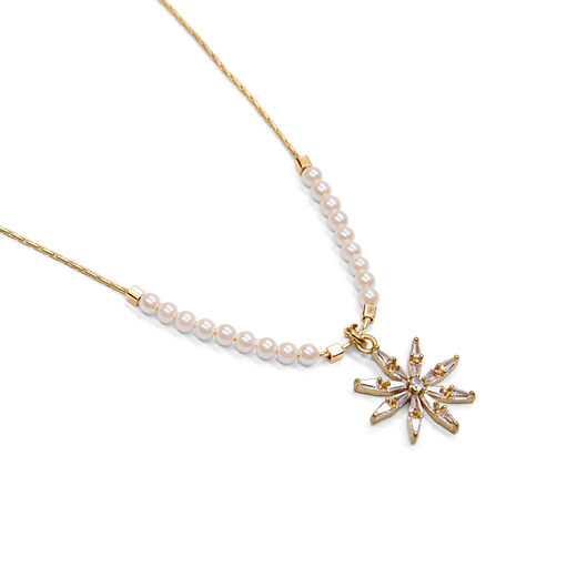 Detail of a star shaped pendant featuring crystals on a gold chain.