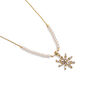 Detail of a star shaped pendant featuring crystals on a gold chain.