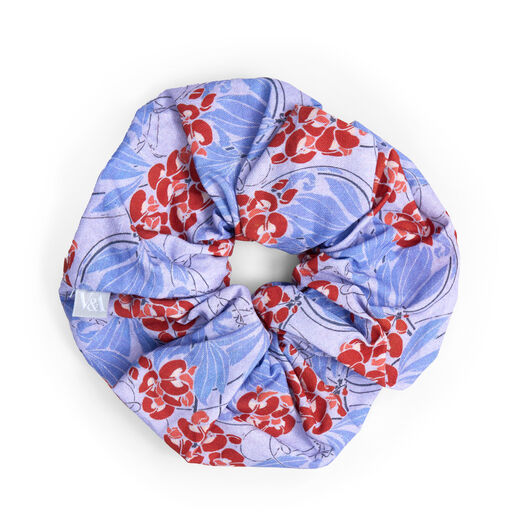 A blue hair scrunchie featuring a botanical pattern with red flowers.