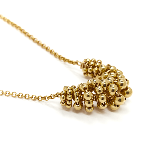 A close up of the gold pendant of a chain necklace.