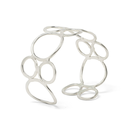 A silver cuff bracelet made up of hoops of various sizes, propped standing on a white top.