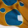 A detail shot of a yellow scarf with a motif of blue circles.