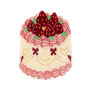 A hair claw in the shape of a tall whipped cream cake topped red strawberries.