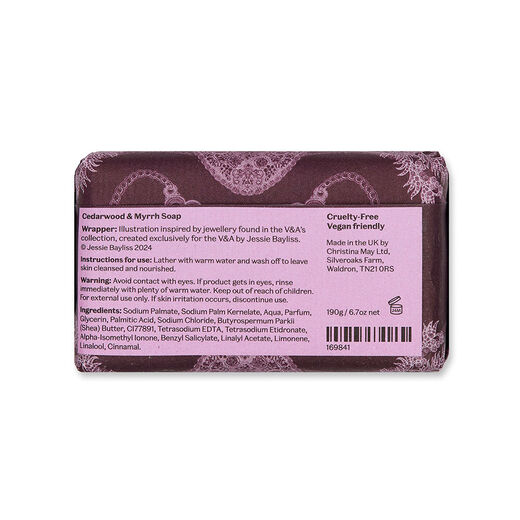 The back of a soap bar wrapped in a purple and pink paper wrapping showing the ingredients list.