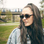 A woman with long brown hair wearing a pair of brown sunglasses.