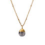 A gold chain necklace with a round shaped black and grey gleaming pendant. 