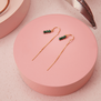 Pull through earrings featuring three green beads on a gold chain