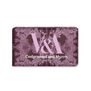 A soap bar wrapped in a purple and pink paper wrapping featuring an intricate illustration of jewellery and the V&A logo.