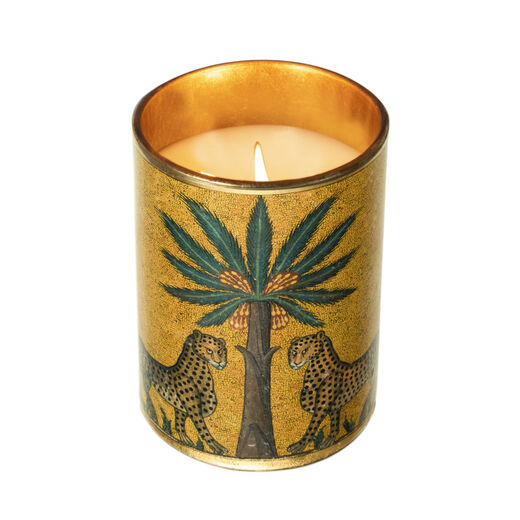 A lit up candle in a cylindric golden jar.