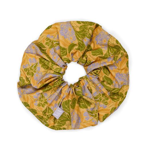 A yellow hair scrunchie featuring a botanical pattern with blue and green daisies.