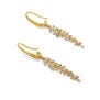 A detail of a pair of hook gold earrings. Each features a pendant in the shape of a long leaf branch with crystals.