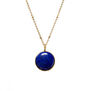 Gold chain necklace featuring a round deep blue pendant.
