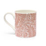 A white china mug with a pattern featuring a pink pattern of Larkspur flowers