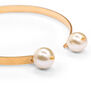 Detail of a gold bracelet featuring two white faux pearls pendants.