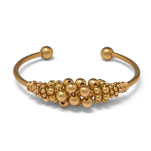 A gold plated cuff bracelet adorned with gold beads.