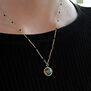 Close up of a white woman's neck, wearing a chain necklace on a black top.