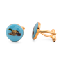 A pair of gold and blue cufflinks featuring an enamel illustration of a duck.