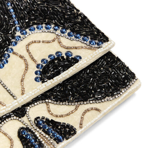 A close up of a clutch bag embellished with a pattern of blue and black beads.