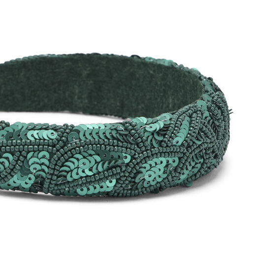 A close up of a sparkly headband, embellished with green sequins.