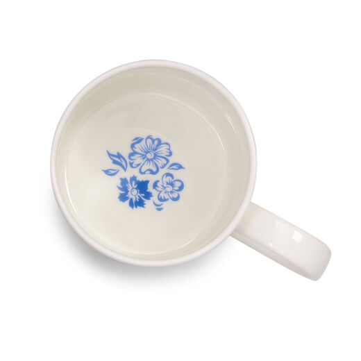 The inside of a white china mug with a blue flower printed at its bottom.