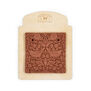 A terracotta tile attached to a backing card. The tile features a floral design with two birds.