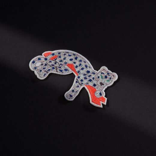 The likeness of a diamond-studded panther lounging on a branch hand sewn in silver, blue, and terracotta threads