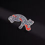 The likeness of a diamond-studded panther lounging on a branch hand sewn in silver, blue, and terracotta threads