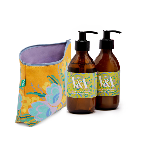 Two brown bottles of beauty products with a green Art Deco label are propped next to a yellow floral zip pouch.
