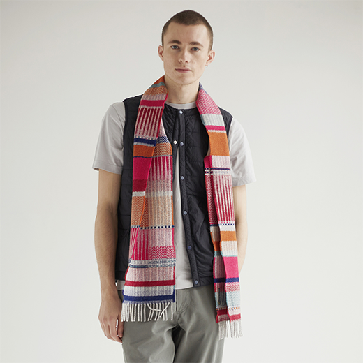 A white man with shaved hair modelling a multicoloured winter scarf.