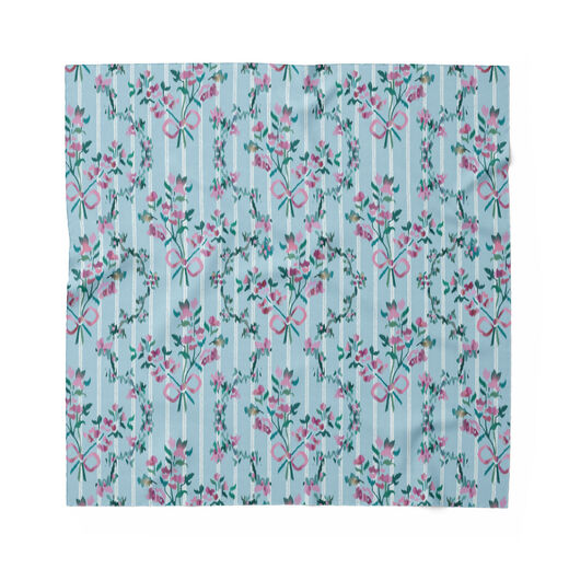 A pale blue square scarf featuring a pattern with pink flowers and red bows on a pale blue background.