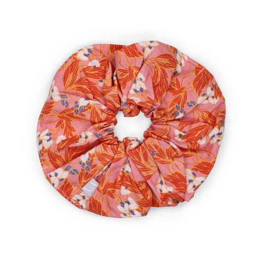 A salmon pink scrunchie featuring a botanical pattern with red flowers.