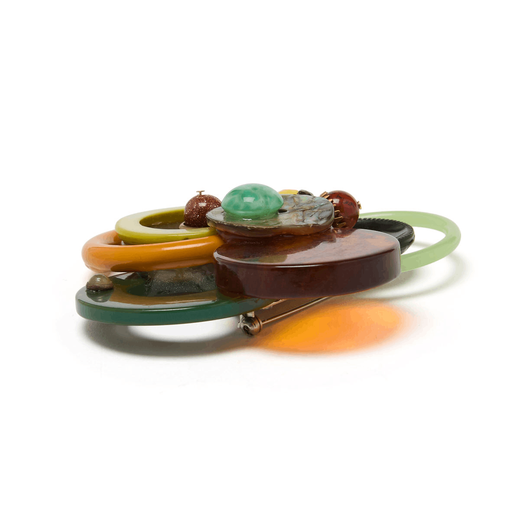 A side view detail of the back of a brown and green brooch.