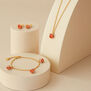 A matching jewellery set consisting of a gold chain necklace, a bracelet and a pair of earrings with rose buds pendants.