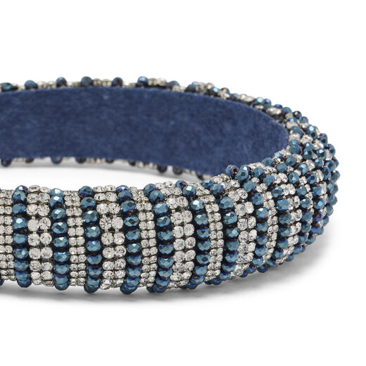A close up of a statement headband encrusted with silver and blue beads.