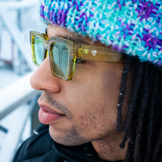 A young man wearing a pair of green sunglasses with thick frame.