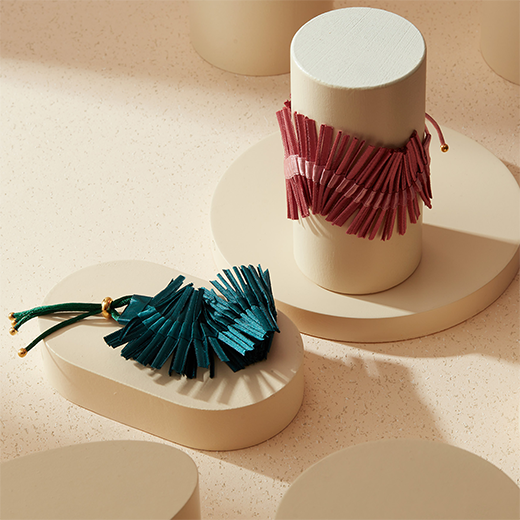 Two bracelets propped on a cream coloured tabletop.