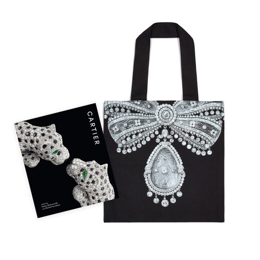 A set including a black tote bag featuring a bow shaped jewel and a book with a black cover. 